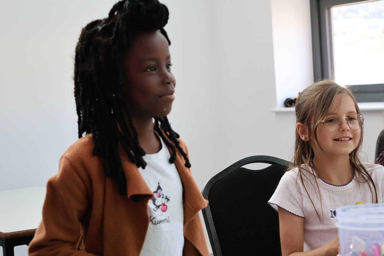 Two girls sitting together and smiling during a session.