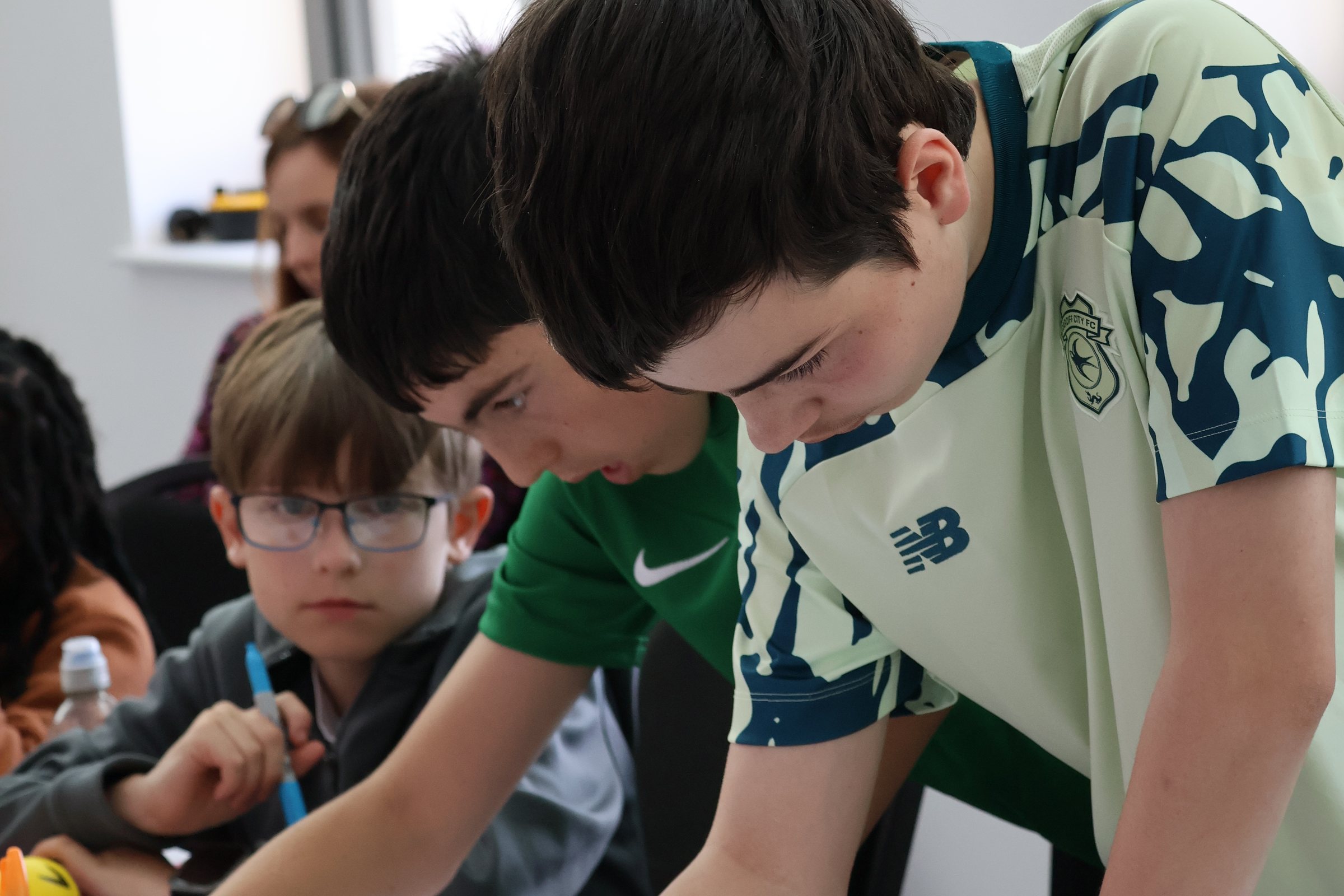 Several young people leaning in together over a shared task, absorbed in what they are doing.