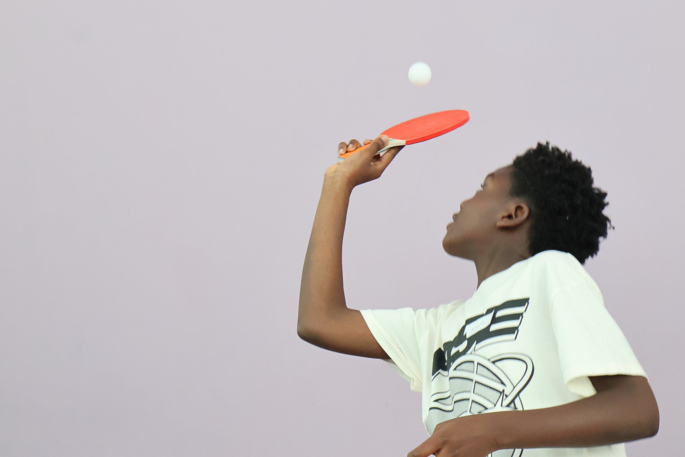 A boy watching the ball as he plays table tennis.